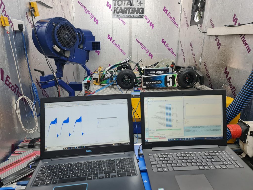 Total Karting Zero e-kart on the team dynamometer with two laptops showing data.